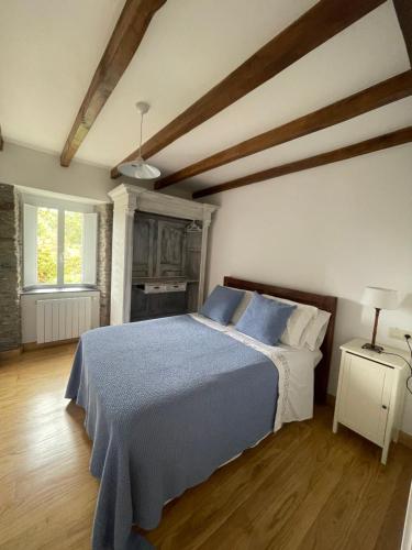 1 dormitorio con cama con sábanas azules y ventana en Casa La Falca en Ortigueira., en Santa Marta de Ortigueira