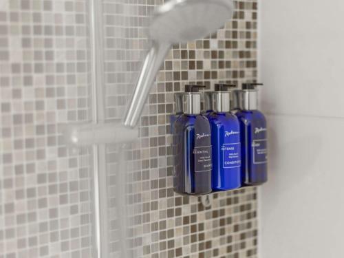 two blue bottles ofodorizers are sitting in a shower at Radisson Blu Arlandia Hotel, Stockholm-Arlanda in Arlanda