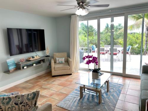 a living room with a tv and a couch and a table at SeaSide Townhome, Spacious 2br 3bath Leeward Grace Bay, Providenciales, walk to beach in Providenciales