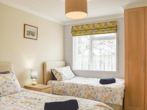 a small bedroom with two beds and a window at Buckland Lodge in Pentridge