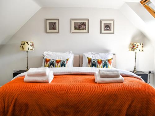 pomarańczowe łóżko w białym pokoju z 2 lampami w obiekcie Summerleaze House w mieście Bude