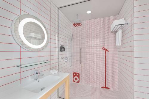 a bathroom with a shower and a sink and a mirror at Radisson RED Dubai Silicon Oasis in Dubai