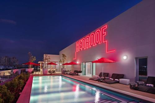 a hotel with a swimming pool and a neon sign at Radisson RED Dubai Silicon Oasis in Dubai