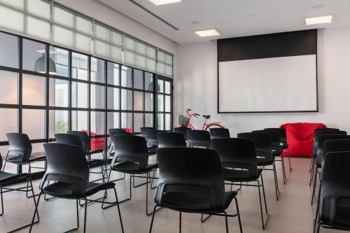 a conference room with black chairs and a screen at Radisson RED Dubai Silicon Oasis in Dubai