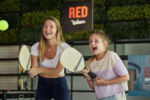 a woman and a little girl holding tennis rackets at Radisson RED Dubai Silicon Oasis in Dubai
