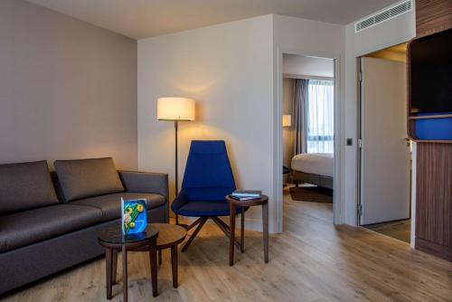 a living room with a couch and a blue chair at Radisson Blu Hotel, Rouen Centre in Rouen