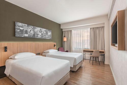 a hotel room with two beds and a table at Park Inn By Radisson Bacolod in Bacolod