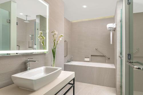 baño blanco con lavabo, bañera y tubermott en Park Inn By Radisson Bacolod en Bacolod