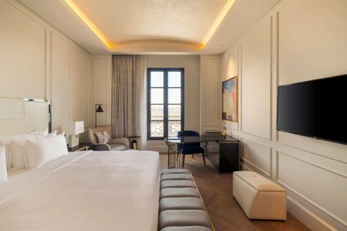 a hotel room with a large bed and a flat screen tv at Mansard Riyadh, a Radisson Collection Hotel in Riyadh