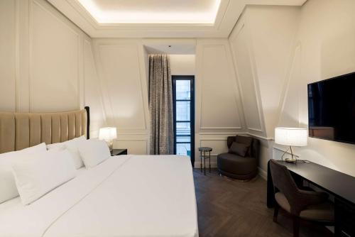 a bedroom with a bed and a desk and a television at Mansard Riyadh, a Radisson Collection Hotel in Riyadh