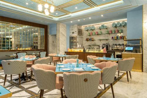 a restaurant with tables and chairs and a counter at Mansard Riyadh, a Radisson Collection Hotel in Riyadh