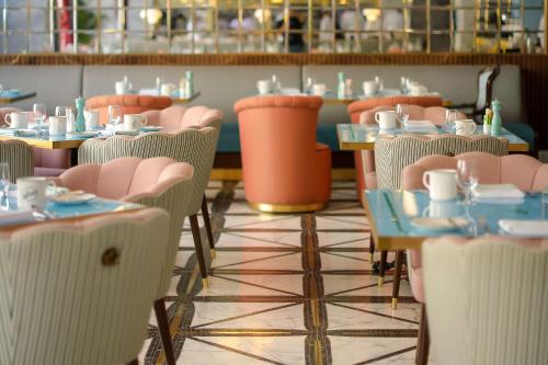 a restaurant with pink chairs and tables with cups on them at Mansard Riyadh, a Radisson Collection Hotel in Riyadh