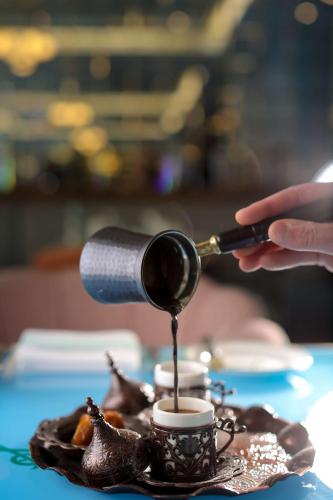 a person pouring coffee into a cup on a table at Mansard Riyadh, a Radisson Collection Hotel in Riyadh