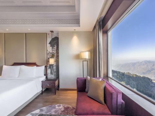 a hotel room with a bed and a large window at Radisson Kufri in Shimla