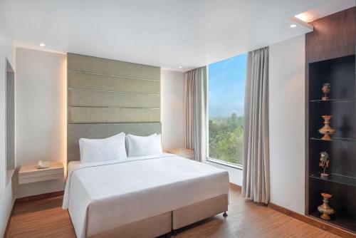 a bedroom with a large bed and a large window at Radisson Hotel Bareilly Airport in Bareilly