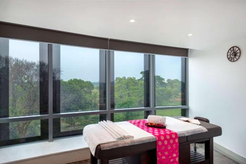 a dining room with a table and large windows at Radisson Hotel Bareilly Airport in Bareilly