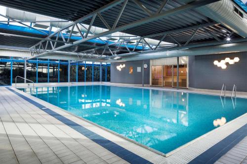 uma grande piscina com água azul num edifício em Radisson RED London Heathrow em Harmondsworth