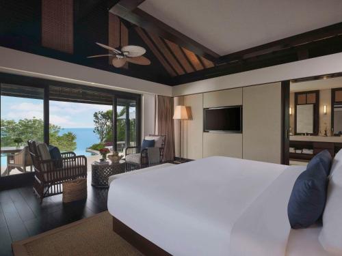 a bedroom with a large white bed and a living room at Raffles Bali in Jimbaran