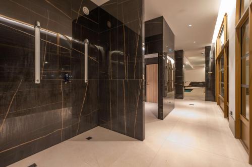 a bathroom with black tiled walls and a walk in shower at Radisson Blu Grand Hotel & Spa, Malo-Les-Bains in Dunkerque