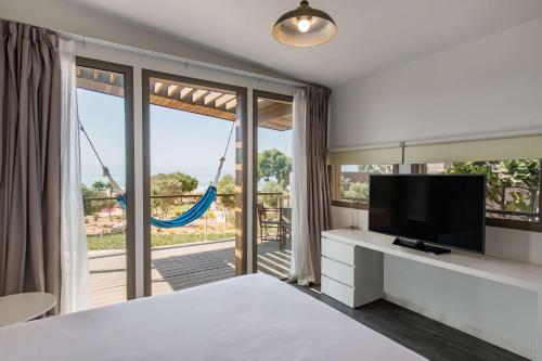 a bedroom with a bed and a tv and a balcony at Radisson Blu Resort Taghazout Bay Surf Village in Taghazout