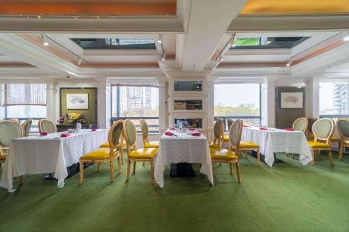 um quarto com mesas brancas, cadeiras amarelas e janelas em Ramada Yichang Hotel em Yichang