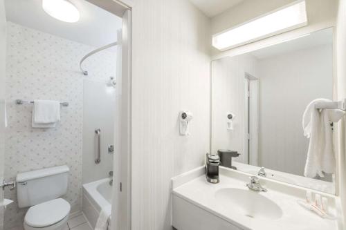 a bathroom with a sink and a toilet and a mirror at Days Inn by Wyndham West Des Moines - Clive in Clive