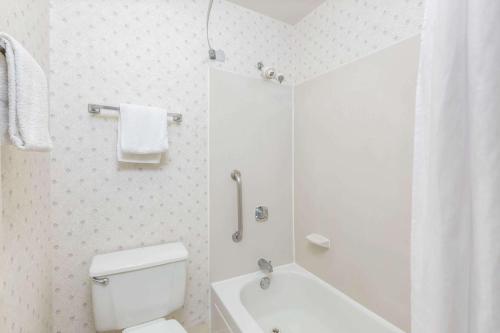 a white bathroom with a toilet and a tub and a sink at Days Inn by Wyndham West Des Moines - Clive in Clive