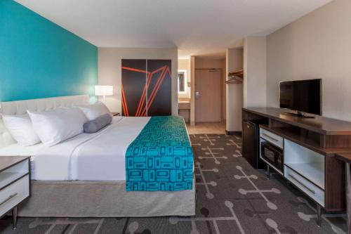 Howard Johnson by Wyndham Romulus Detroit Metro Airport في رومولوس: غرفة فندقية بسرير وتلفزيون بشاشة مسطحة