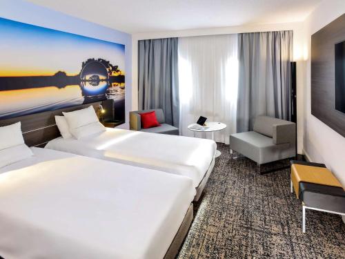 um quarto de hotel com duas camas e uma cadeira em Novotel Toulouse Centre Compans Caffarelli em Toulouse