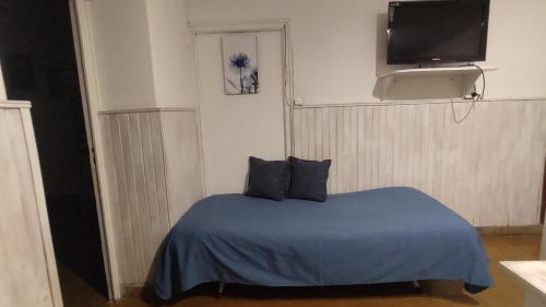 a bedroom with a blue bed with a tv on the wall at Departamento Gutiérrez in Maipú