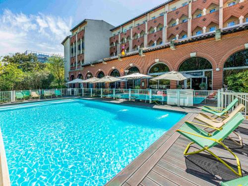 una gran piscina con sillas y un edificio en Novotel Toulouse Centre Compans Caffarelli, en Toulouse