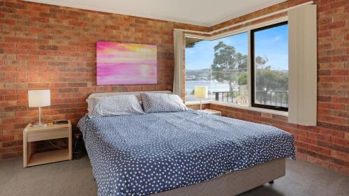 a bedroom with a bed and a brick wall at Unit 6 52 Fishpen Road, Merimbula in Merimbula