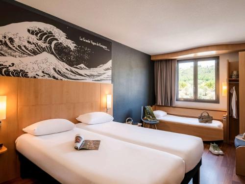 a hotel room with two beds and a wave on the wall at IBIS Cannes Mouans Sartoux Piscine parking gratuit in Mouans-Sartoux