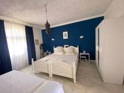 a bedroom with a white bed and a blue wall at Gozo Holiday Apartmen - 2 Bedroom Villa with Shared Pool in Xagħra