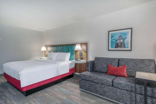 ニュー・フィラデルフィアにあるHampton Inn New Philadelphiaのベッドとソファ付きのホテルルーム