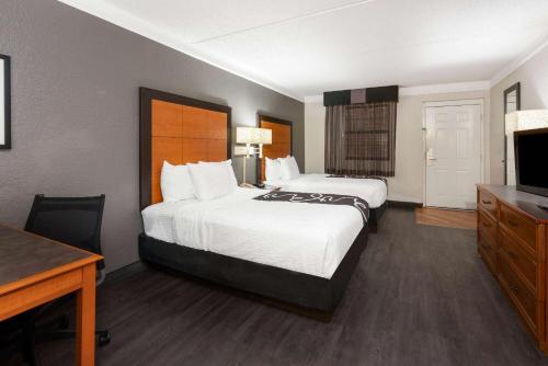 a hotel room with two beds and a desk and a television at Super 8 by Wyndham The Woodlands North in The Woodlands