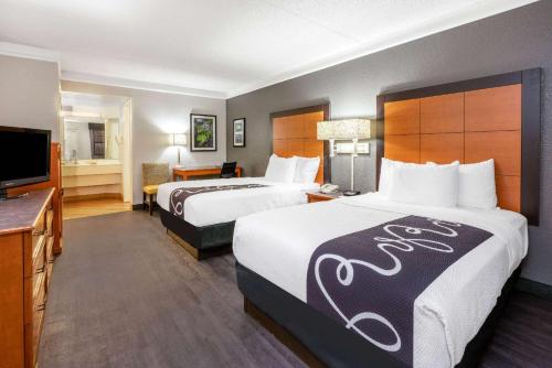a hotel room with two beds and a flat screen tv at Super 8 by Wyndham The Woodlands North in The Woodlands