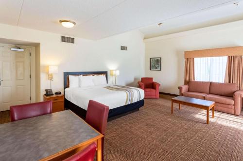 a hotel room with a bed and a couch and a table at La Quinta Inn by Wyndham Huntsville Research Park in Huntsville