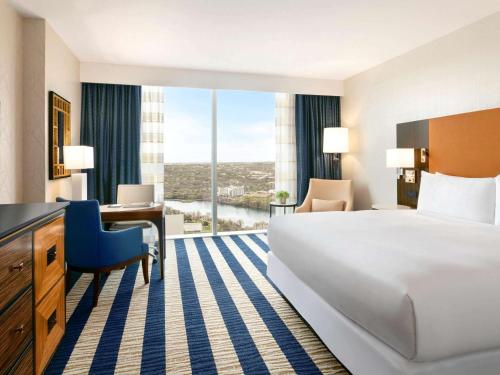 オースティンにあるFairmont Austinの大きなベッドとデスクが備わるホテルルームです。