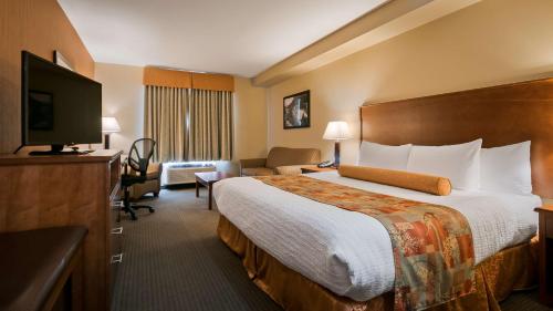 Habitación de hotel con cama y TV de pantalla plana. en Best Western Plus Service Inn & Suites, en Lethbridge
