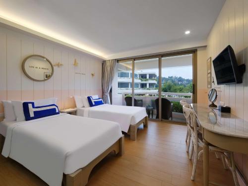 a hotel room with two beds and a desk at HOMM Bliss Southbeach Patong in Patong Beach