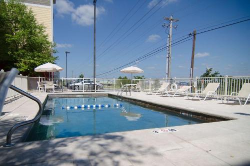 a small swimming pool with chairs and umbrellas at MainStay Suites St Robert-Fort Leonard Wood in Saint Robert
