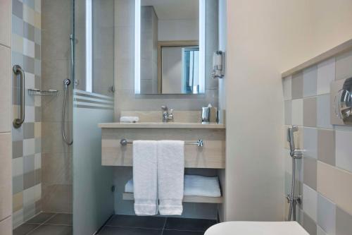 ein Badezimmer mit einem Waschbecken, einem WC und einem Spiegel in der Unterkunft Hampton By Hilton Doha Old Town in Doha