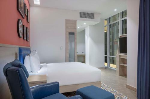 a bedroom with a white bed and a blue chair at Hampton By Hilton Doha Old Town in Doha