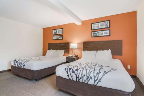 two beds in a hotel room with orange walls at Sleep Inn & Suites Ronks in Ronks