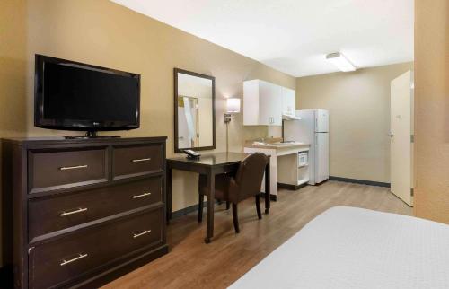 a room with a desk with a television and a bedroom at Extended Stay America Select Suites - Roanoke - Airport in Roanoke