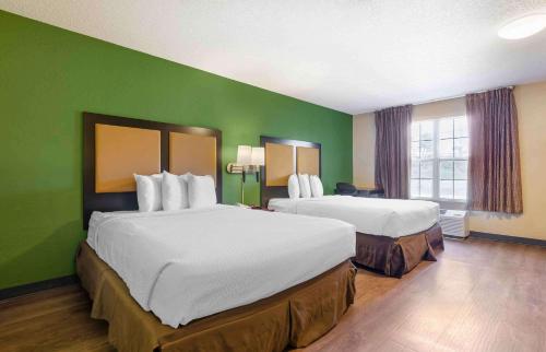 ein Hotelzimmer mit 2 Betten und einer grünen Wand in der Unterkunft Extended Stay America Select Suites - Roanoke - Airport in Roanoke