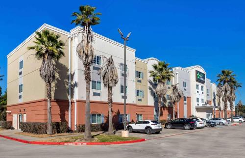 a building with palm trees in front of a parking lot at Extended Stay America Suites - Houston - Kingwood in Kingwood