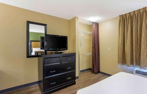 a room with a television and a dresser with a mirror at Extended Stay America Select Suites - Springfield - South in Springfield