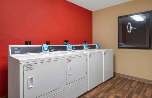 una fila de lavadoras en una habitación con una pared roja en Extended Stay America Suites - Indianapolis - Airport - W Southern Ave, en Indianápolis